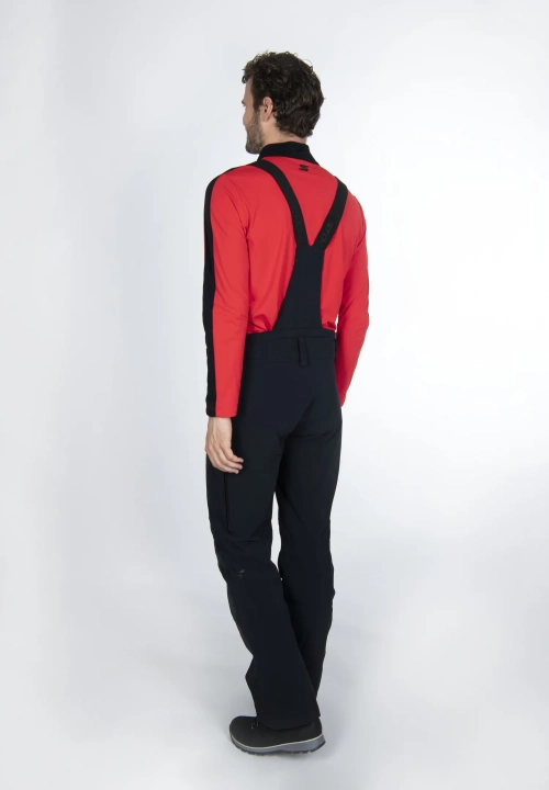 Model od tyłu w spodniach STOECKLI SKI PANT RACE BLACK LONG, widoczne odpinane szelki.