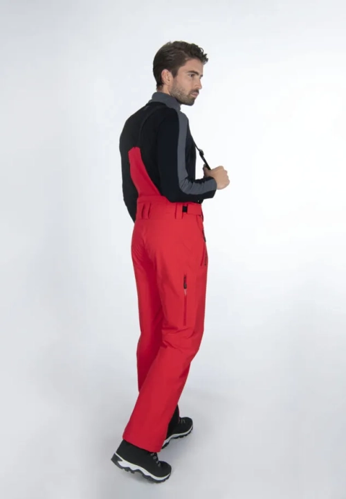 Model w czerwonych spodniach STOECKLI SKI PANT RACE RED, widok z tyłu, widoczne szelki.