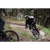 Rowerzysta w czarnym matowym kasku MTB Alpina Taunus MIPS podczas dynamicznej jazdy na rowerze górskim po leśnym szlaku.